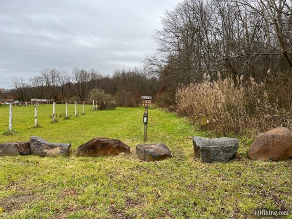 Trail parking area with large rocks lining the edge and a sign.