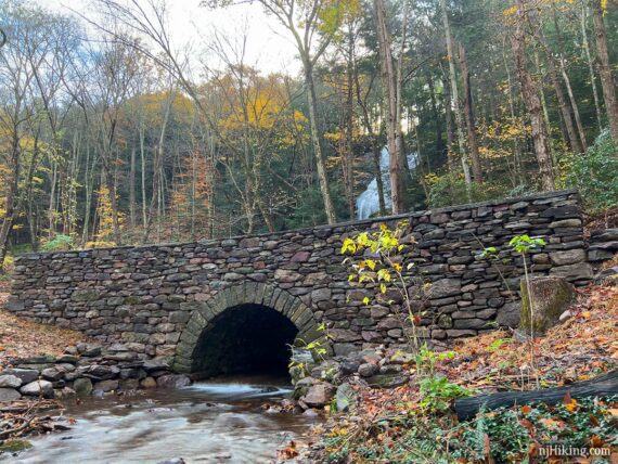 Stream flowing through an arch in a bridge.