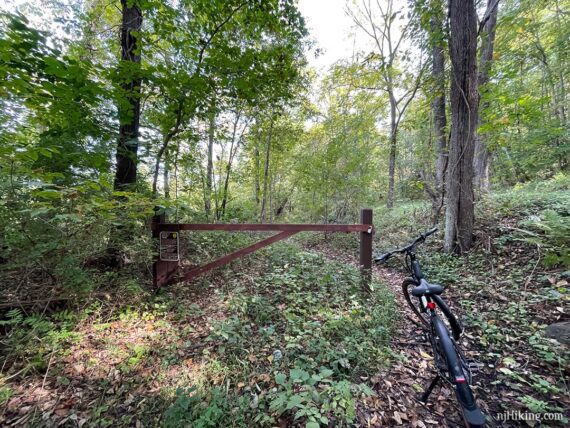 Trail gate with a sign on an overgrown rail-trail.