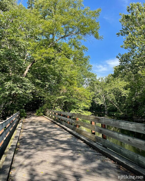 Wooden bridge with a stream visible on the right side.