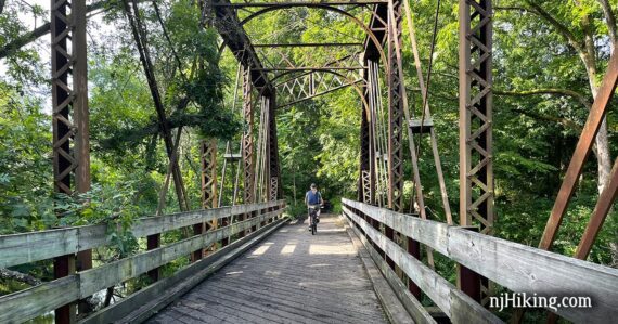 Bike rider on a large wooden bridge with metal overhead.