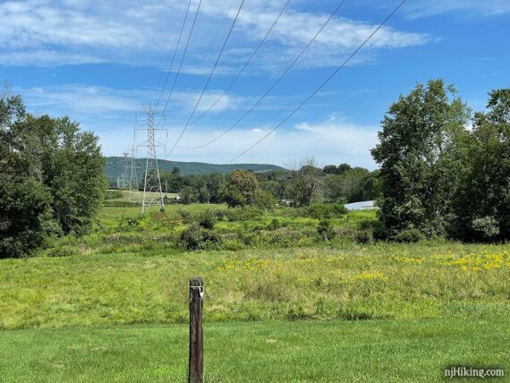 Tall power lines crossing an open field and leading off in the distance.