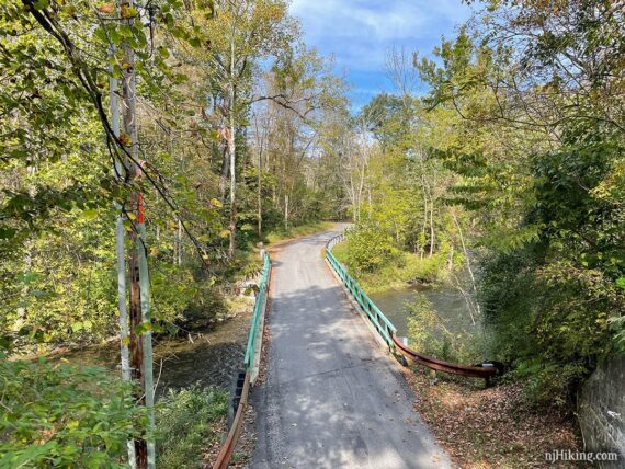 A road below seen from a rail-trail  up on a bridge.