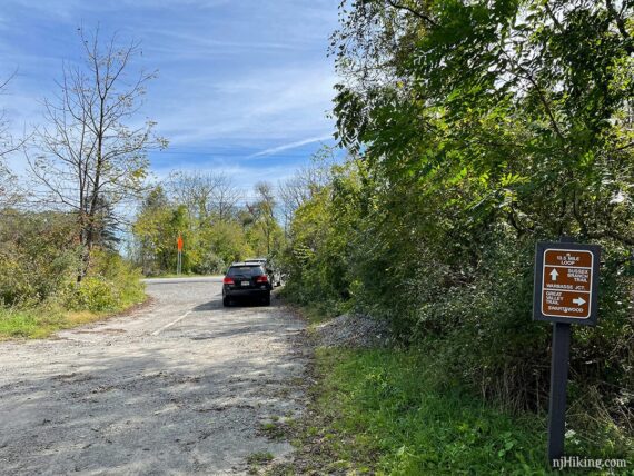 Parking area with a sign for the intersection of two rail-trails.