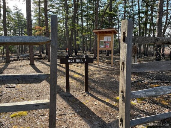 Trailhead for Sand and Water Trail at a break in a wooden fence.